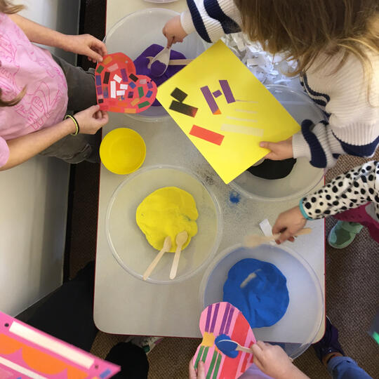 Children using bright coloured sand laid out on table