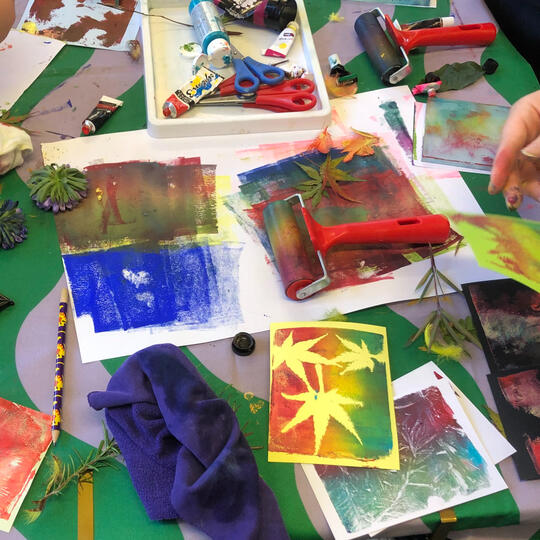 Parent and child working together to cut and collage using bright printed papers