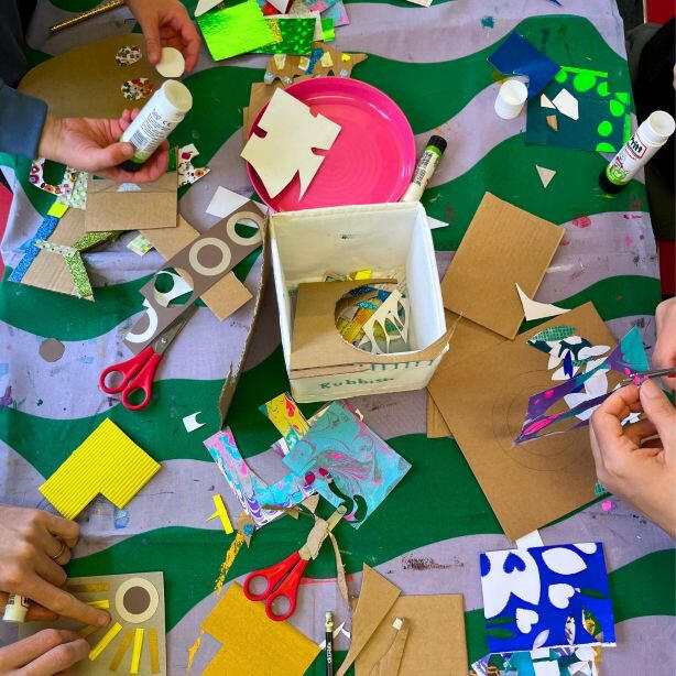 Adult and child hands creating colourful paper collages at a family arts and crafts workshop